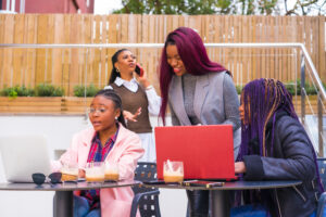 African-American females at a business meeting in a cafeteria with laptops and coffee on the table